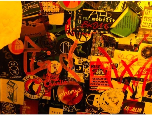 Berlin graffiti collage with layered stickers and tags in yellow and red tones